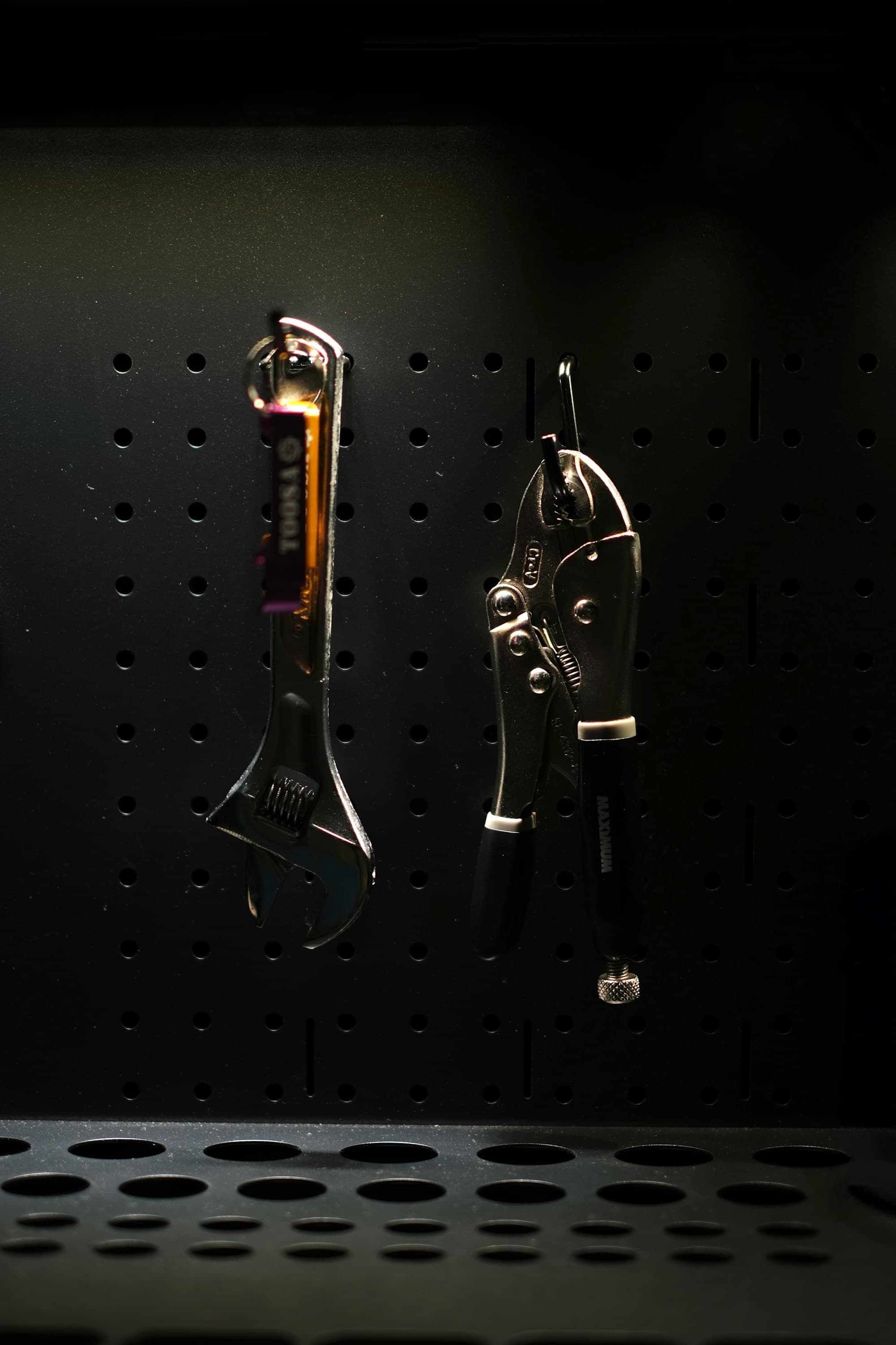 Wrench and pliers hanging on a pegboard