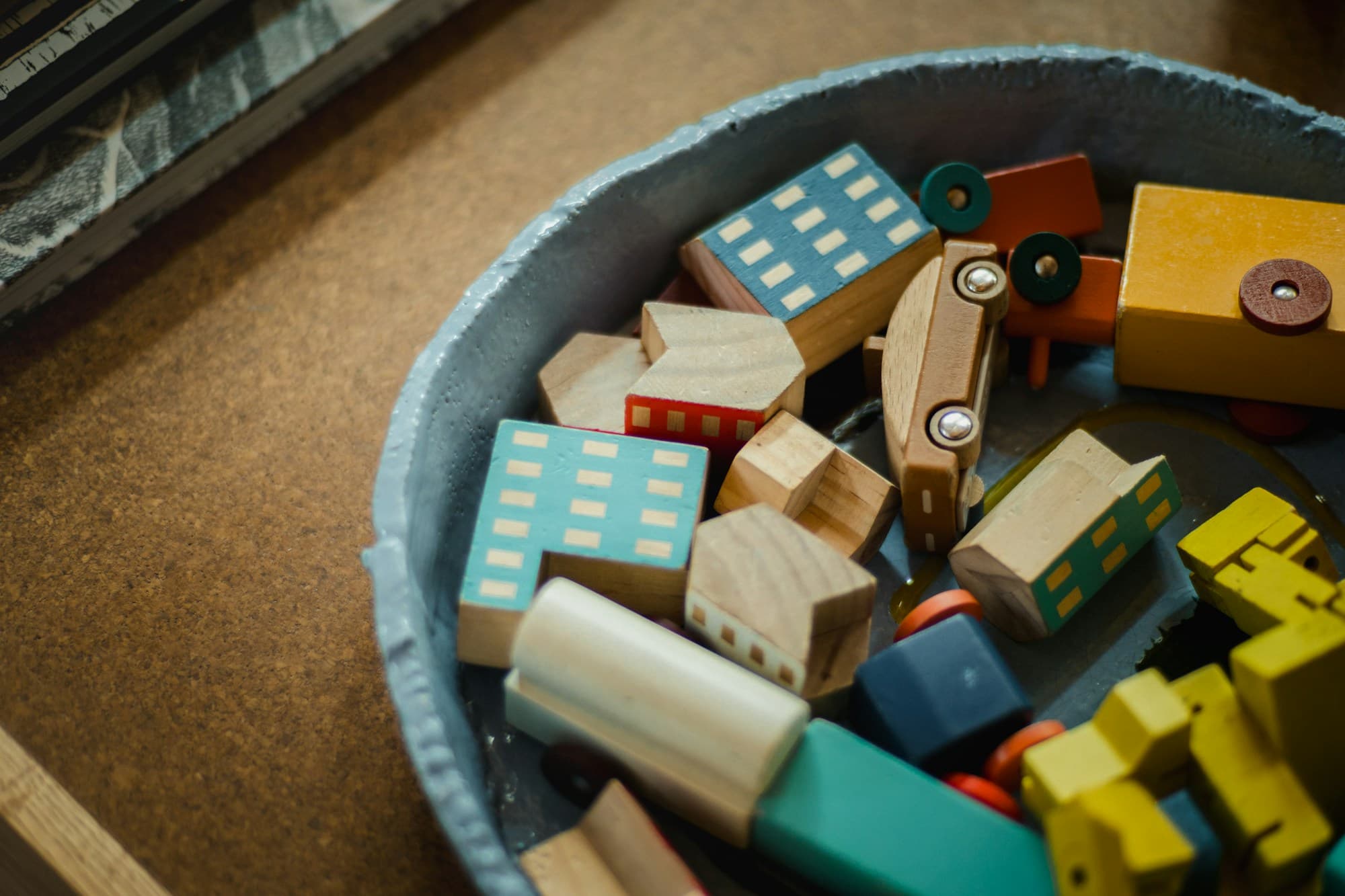 A basket of colourful wooden building blocks and toy cars